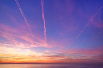 Fototapeta na wymiar Bewitching magical gradient sky with plane traces after sunset