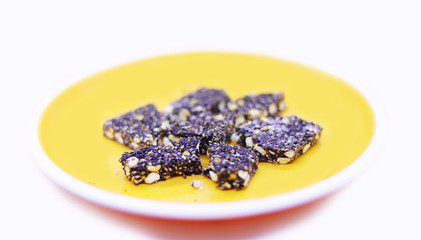Indian Traditional Sweet Peanut Barfi, Ellu Mittai in a yellow plate on a white background top view