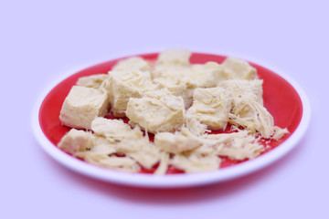 traditional indian candy soan papdi in red plate on a gray background. top view, copy space.