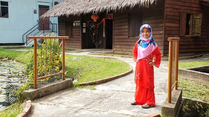 Portrait of young girl wearing traditional dress 'baju kurung' with hijab. Selected focus. Image contain certain grain or noise and soft focus when view at full resolution.