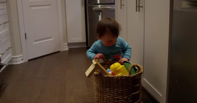 baby boy pushes basket of toys through kitchen - front angle