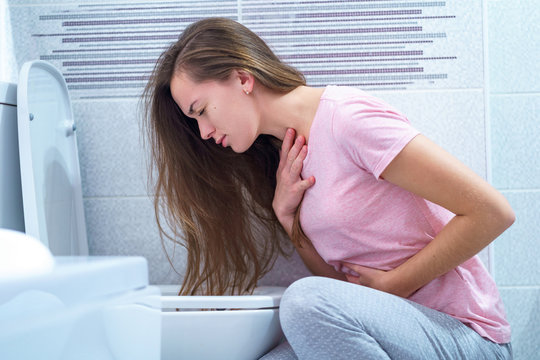 A young woman suffers from nausea and vomiting due to digestive and stomach problems. Morning toxicosis in early pregnancy. Food poisoning and infection