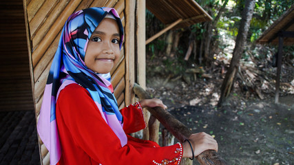 Portrait of young girl wearing traditional dress 'baju kurung' with hijab. Selected focus. Image contain certain grain or noise and soft focus when view at full resolution.