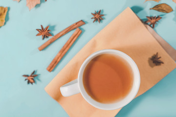 Obraz na płótnie Canvas Autumn composition. Cup of coffee, autumn leaves , cinnamon sticks and anise stars on Bright Blue pastel background. Flat lay, top view copy space.