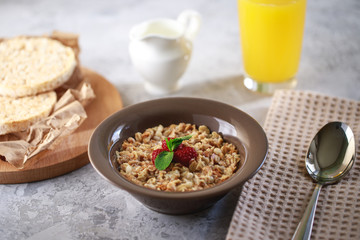 Baked granola with milk and raspberries in a plate, whole grain breads and freshly squeezed juice. Healthy breakfast. Delicious muesli.