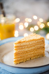 A piece of festive honey cake in a plate decorated with Christmas garlands. Vertical orientation. Selective focus