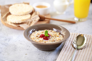 A healthy and dietary breakfast. Baked granola with milk and raspberries in a plate, whole grain breads and freshly squeezed juice. Delicious muesli.