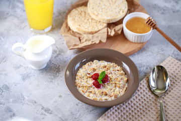 A healthy and dietary breakfast. Baked granola with milk and raspberries in a plate, whole grain breads and freshly squeezed juice. Delicious muesli.