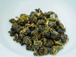 Close up of dry Chinese green oolong tea balls in a white porcelain cup