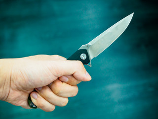 Hand holding a pocket-knife ion dark background