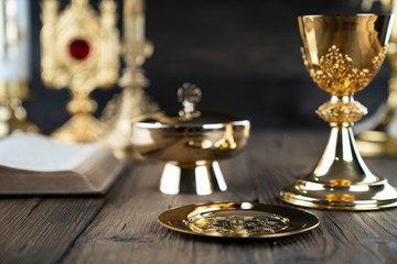 Fototapeta na wymiar Roman Catholic Church theme. The Cross, Holy Bible, monstrance, rosary and golden chalice on rustic wooden table.
