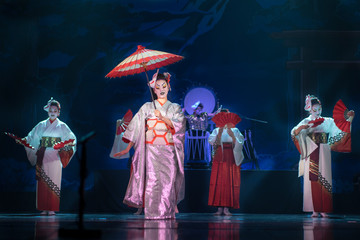 Traditional Japanese performance. Actresses in traditional white and red kimono and fox masks dancing with umbrella and fans.
