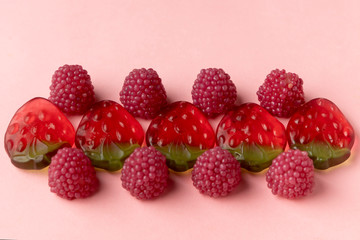 Jelly candies on a pink background. Sweets in the form of strawberries and raspberries in a row. Copy space. Top view.