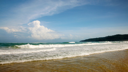 Fototapeta na wymiar Waves, surf, and the blue sky over the sea, Karon sandy beach on a sunny day, Thailand