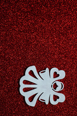 Simple Christmas or winter concept: white, decorative angel, located on the right side red glitter background, selective focus, free copy space