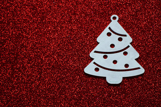 Simple, minimalistic Christmas concept: white christmas tree, located on the right side, dark red glitter background, selective focus, free copy space