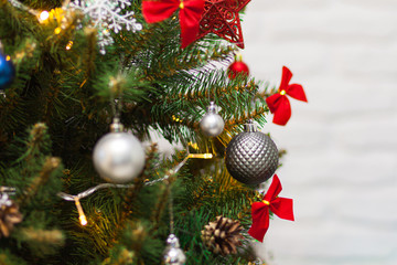 Beautiful green Christmas tree decorated with gray balls and garlands. Close-up photo. Sparkling background