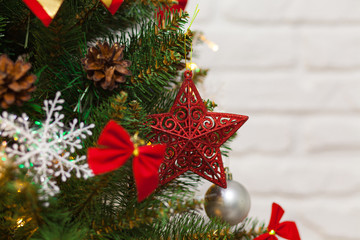 Beautiful green Christmas tree decorated with balls, big red star and garlands. Close-up photo