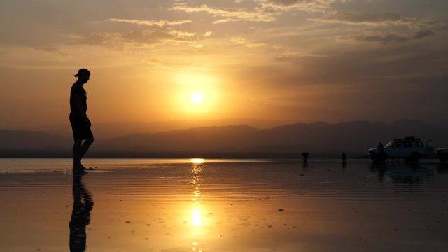 Silhouette of man walking through the Danakil Depression salt flats in Ethiopia during an amazing sunset