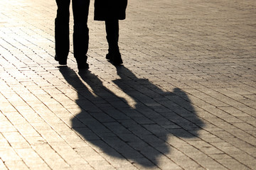 Silhouettes and shadows of couple walking down the street. People on a sidewalk, concept of...
