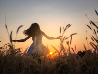 Trendy girl in stylish summer dress feeling free in the field with flowers in sunshine,enjoying nature, Beautiful Teenage Model in the Spring Field, Sun Light.