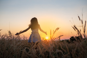 Trendy girl in stylish summer dress feeling free in the field with flowers in sunshine,enjoying nature, Beautiful Teenage Model in the Spring Field, Sun Light.