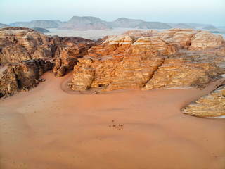 Camels and tourists congregating in the desert of Wadi Rum to watch the sunset in Autumn