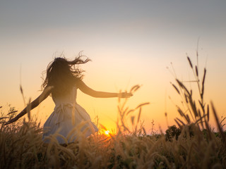 Trendy girl in stylish summer dress feeling free in the field with flowers in sunshine,enjoying nature, Beautiful Teenage Model in the Spring Field, Sun Light.