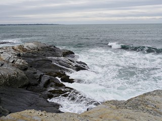 Fototapeta na wymiar Foaming waves rolling toward rocky shores