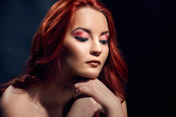 Romantic redheaded woman with bright makeup, perfect skin and curly hair