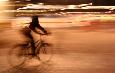 A Young Girl Riding a Bicycle at Night