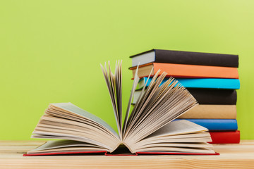 Simple composition of many hardback books, raw of books on wooden table and light green background