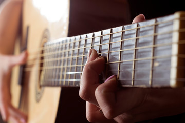 Teen girl playing an acoustic guitar. fingers in manicure on frets
