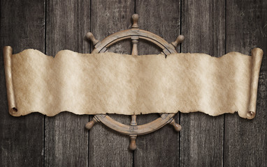 Old pirates map scroll and steering-wheel over wood background. Mixed media.