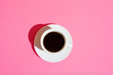 White Cup of Black Coffee with Saucer on Fuchsia Pink Color Background. Top View. Morning Breakfast Energy Caffeine Addiction Concept. Trendy Minimalist Style Hard Sunlight. Pop Art 80s Style