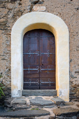 Fototapeta na wymiar Medieval brown wooden door of a rustic stone building