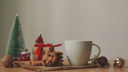 Obraz na płótnie Canvas White mug with Chocolate cookies and Gift box on wood table. Christmas.