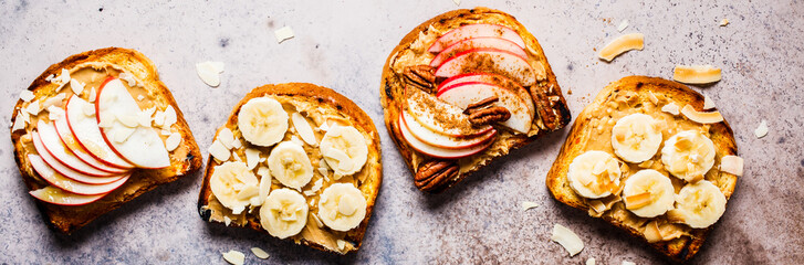 Peanut butter toasts with banana and apple on a gray background, flat lay.