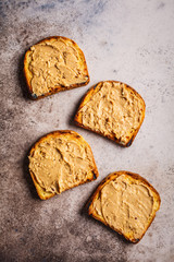 Crispy peanut butter toasts on a gray background, flat lay.