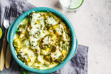 Broccoli casserole with cheese in blue dish, gray background. Vegetarian food concept.