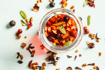 Berry pink tea with herbs in glass jar, white background. Healthy drinks content.
