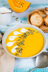 Pumpkin soup puree with pumpkin seeds and wheat croutons in the center of the frame. Vertical photo