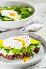 Poached egg toast with avocado, cream cheese and rye bread on gray plate. Healthy food concept.