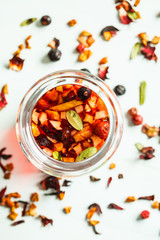 Berry pink tea with herbs in glass jar, white background. Healthy drinks content.