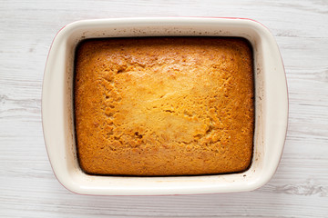 Homemade sweet Cornbread in a dish over white wooden surface, top view. Flat lay, overhead, from above. Close-up.