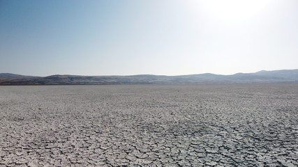 Bottom of a dried-out lake and cracked ground. Clear sky and hills