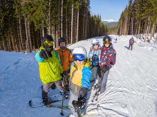 group of people with snowboards and skis taking selfie on the top of the hill