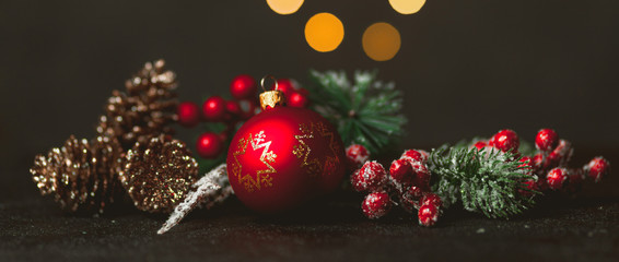 New Year and Christmas decoration, holiday background. Red festive ball bauble, green fir (xmas tree) and yellow blurred lights. Toned on vintage style.