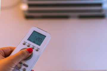remote control from the air conditioner in a woman's hand