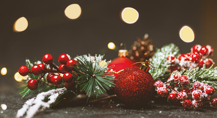 New Year and Christmas decoration, holiday background. Red festive ball bauble, green fir (xmas tree) and yellow blurred lights. Toned on vintage style.